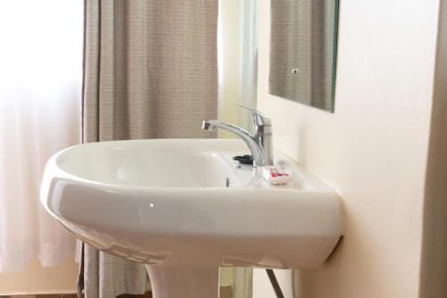 lavabo blanco en el baño con espejo en Mayas Suites en Nyeri