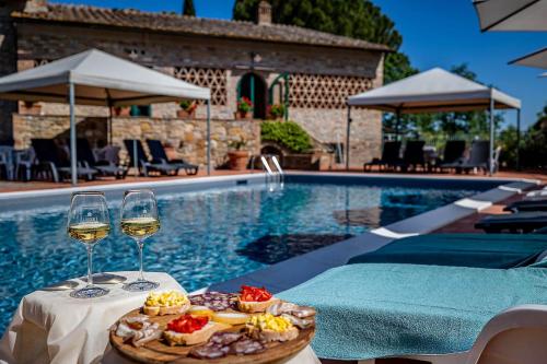 una mesa con un plato de comida y dos copas de vino en La Fornace Di Racciano, en San Gimignano