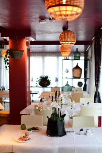una sala da pranzo con un tavolo con sopra dei fiori di Hotel Maarea a Milano Marittima