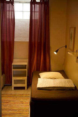 1 dormitorio con 1 cama con cortinas rojas y ventana en Gamla stans Hostel, en Estocolmo