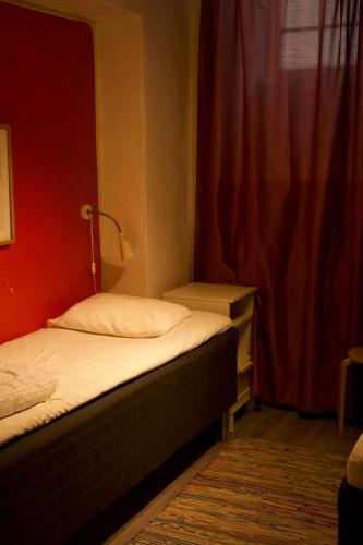 1 dormitorio con 2 camas y pared roja en Gamla stans Hostel, en Estocolmo