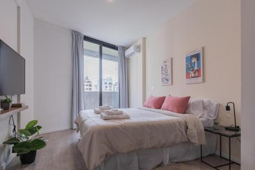 1 dormitorio blanco con 1 cama grande con almohadas rosas en Fliphaus Guateflat 'e' - 1 Bd Palermo Soho en Buenos Aires