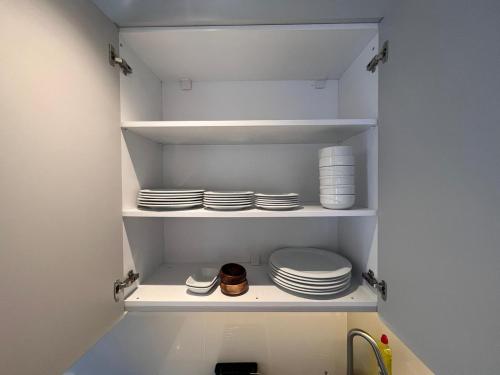 a pantry with white plates and dishes on shelves at Ulu Panorama Residence in Alanya
