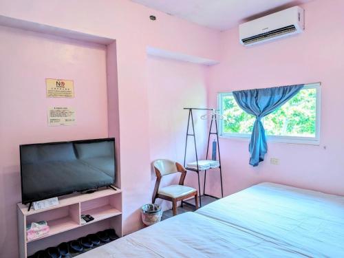 Schlafzimmer mit einem Bett, einem TV und einem Stuhl in der Unterkunft A-Lang Homestay in Lanyu