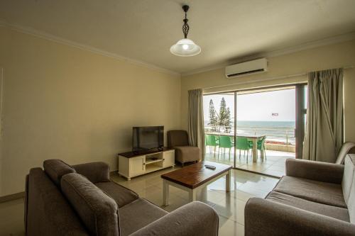 a living room with a couch and a tv and a balcony at Saints View Resort Unit 22 in Uvongo Beach