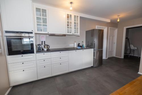 a kitchen with white cabinets and a stainless steel refrigerator at Bjarnabúð in Húsavík