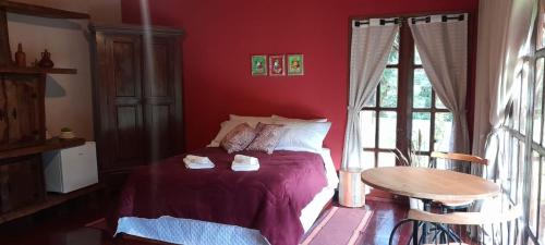 a bedroom with a bed and a table and a window at Pousada Bosque do Visconde in Visconde De Maua