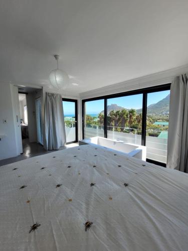 a bedroom with a large white bed with a large window at LA HACIENDA - MODERN, BRIGHT, STYLISH House with Private Pool in Cape Town