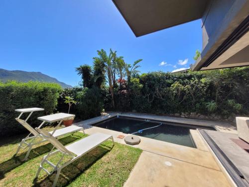 a small swimming pool with a table and a chair at LA HACIENDA - MODERN, BRIGHT, STYLISH House with Private Pool in Cape Town