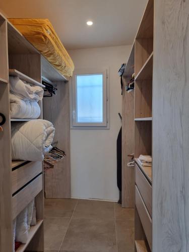 Elle comprend un dressing avec des étagères en bois et une fenêtre. dans l'établissement Maison 3 chambres climatisé + garage, à Roquebrun