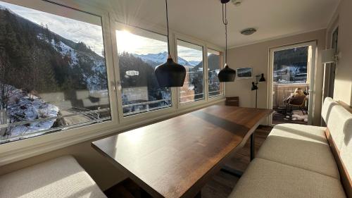a dining room with a table and a large window at Exclusive Panorama Spa Suiten DAS SCHILLER in Bad Gastein