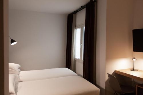 a hotel room with two beds and a window at Alexandra Barcelona Hotel, Curio Collection by Hilton in Barcelona
