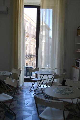 ein Zimmer mit Tischen und Stühlen und einem Fenster in der Unterkunft Il Teatro Rooms in Catania