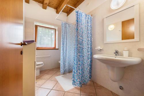 La salle de bains est pourvue d'un rideau de douche bleu et d'un lavabo. dans l'établissement Bilo Garden Agriturismo Teboi, à Pastrengo