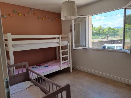 une chambre avec deux lits superposés et une fenêtre dans l'établissement Maison 3 chambres climatisé + garage, à Roquebrun