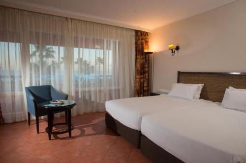 Porto Sokhna Resort في العين السخنة: غرفه فندقيه بسرير وكرسي وطاولة