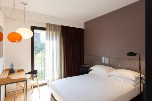 a hotel room with a bed and a desk and a window at Alexandra Barcelona Hotel, Curio Collection by Hilton in Barcelona