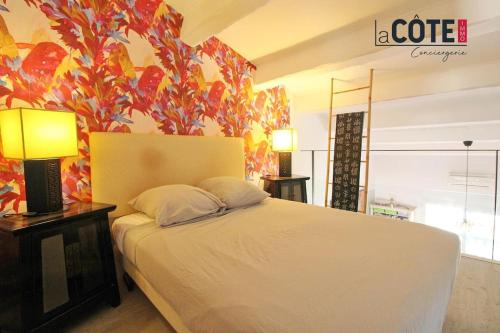 - une chambre avec un lit blanc et un mur fleuri dans l'établissement Amphore bis, à Sausset-les-Pins