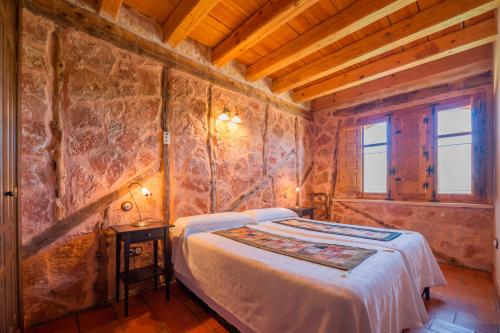 a bedroom with a bed and a stone wall at Los Lebreles Namaste I y II, desconecta en las Hoces del Duratón in Hinojosas del Cerro