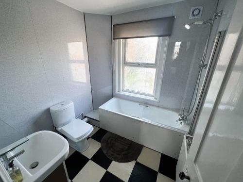 a bathroom with a toilet and a tub and a sink at George Street House in Ryde
