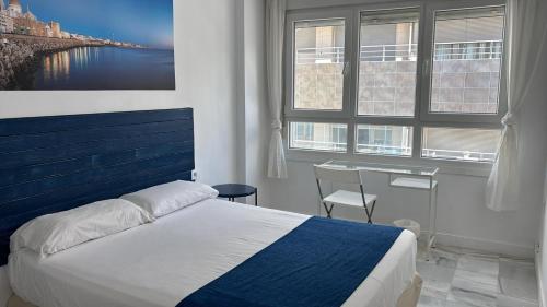 sypialnia z łóżkiem, stołem i oknami w obiekcie Apartamentos Turisticos Imar w Kadyksie