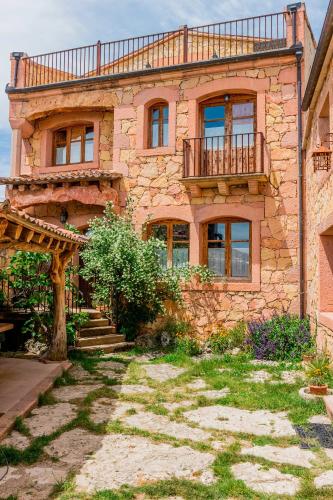 a stone house with a balcony on top of it at Los Lebreles Namaste I y II, desconecta en las Hoces del Duratón in Hinojosas del Cerro