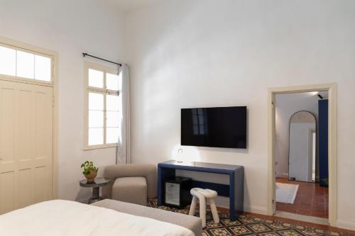 1 dormitorio con 1 cama y TV en la pared en Mila - Boutique Hotel, en Haifa