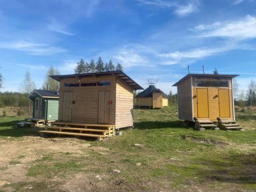 un grupo de pequeñas chozas en un campo en Triangle Cabin, en Laitila