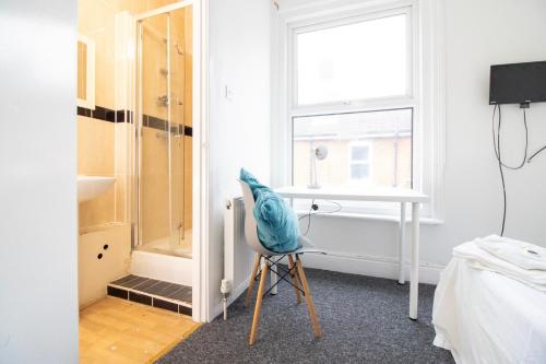 um quarto com uma cadeira, uma secretária e uma janela em Pebbles guest house em Southampton