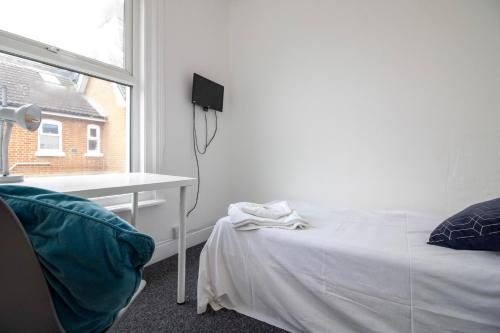 a bedroom with a bed and a desk and a window at Pebbles guest house in Southampton