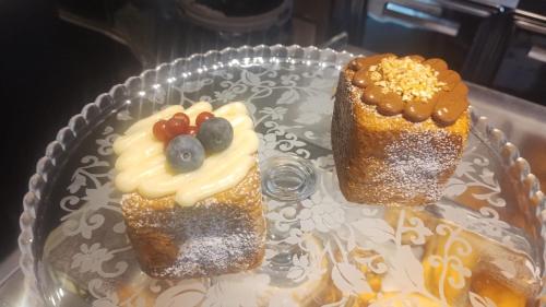 two cakes on a glass plate on a table at Maison Divino in Trani