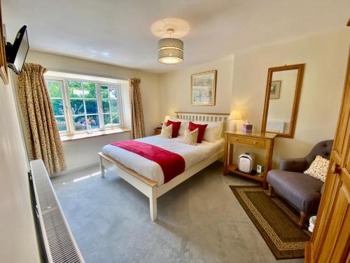 una camera con un letto e una sedia di Lynwood House Bed and Breakfast a Tregoney