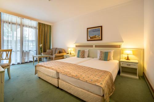 een hotelkamer met een groot bed en een stoel bij Helena Park - Ultra All Inclusive in Sunny Beach