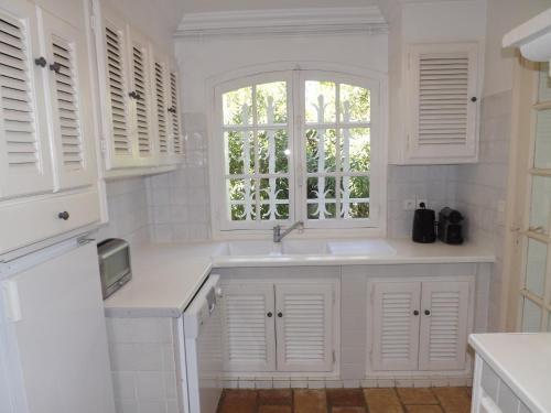 une cuisine blanche avec un évier et une fenêtre dans l'établissement Villa Pampelonne-Ramatuelle, à Saint-Tropez