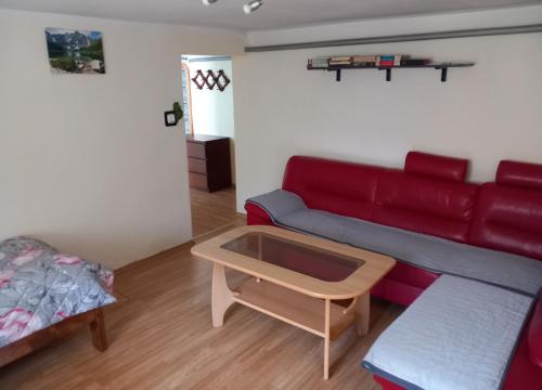 uma sala de estar com um sofá vermelho e uma mesa de centro em Apartament pod Szlakiem em Korbielów