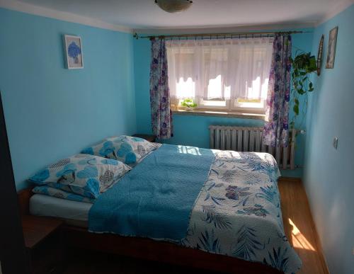 um quarto com uma cama com paredes azuis e uma janela em Apartament pod Szlakiem em Korbielów