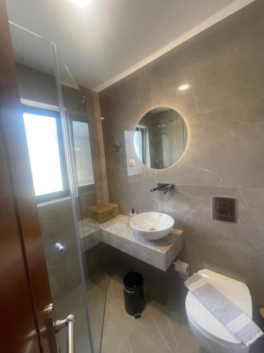 La salle de bains est pourvue d'un lavabo, de toilettes et d'un miroir. dans l'établissement Villas Almyrida, à Almyrida