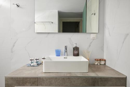 a bathroom with a white sink and a mirror at Votsalo in Ierápetra