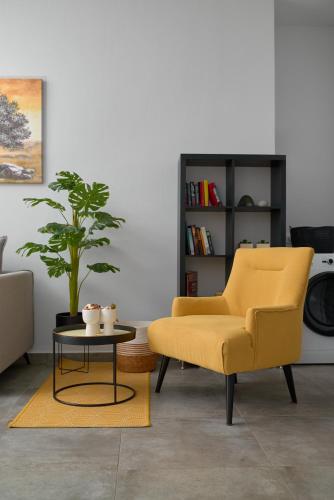 a living room with a yellow chair and a table at Votsalo in Ierápetra