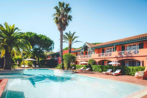 聖特羅佩的住宿－拉斯特拉加勒莊園酒店，棕榈树建筑前的游泳池