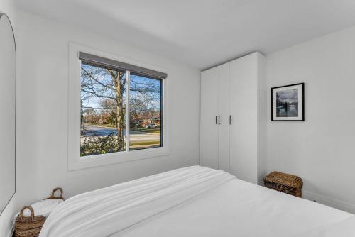 Un dormitorio blanco con una cama y una ventana. en Spacious Elegance: Two Living Spaces in One Home, en Burlington