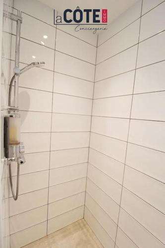 La salle de bains est pourvue d'une douche et de murs carrelés blancs. dans l'établissement Les Grillons, à Sausset-les-Pins