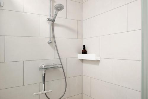 a shower with a shower head in a white tiled bathroom at Neues Apartment am Schloßsee Salem in Salem