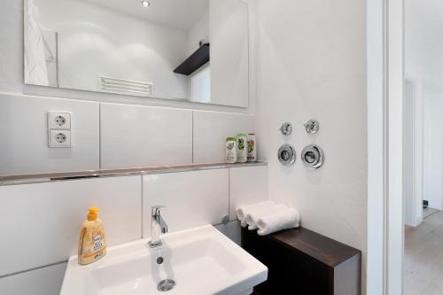 een witte badkamer met een wastafel en een spiegel bij Die Bleichstraße in Pforzheim