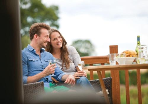 a man and woman sitting at a table with a glass at Wigmore Lakes Lodges in Cardeston