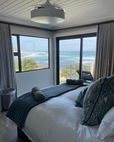 a bedroom with a bed with a view of the ocean at The Cottage in Morganʼs Bay
