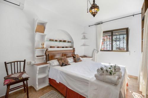 ein Schlafzimmer mit einem Bett und einem Stuhl und einem Fenster in der Unterkunft Villa Al Andalus - Solo Familias in El Puerto de Santa María