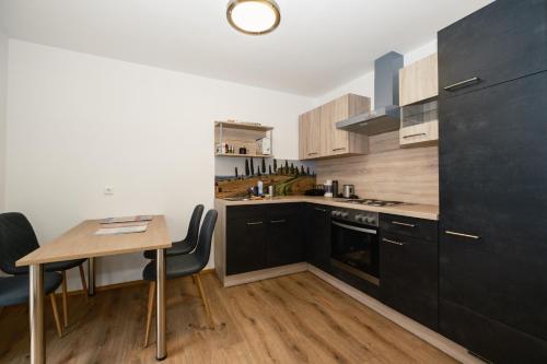 Barnbach的住宿－BÄRNAppartements 2，厨房配有黑色橱柜和桌椅