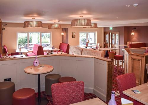 un ristorante con sedie rosse, un bar e tavoli di Brighouse Bay Holiday Park a Kirkcudbright