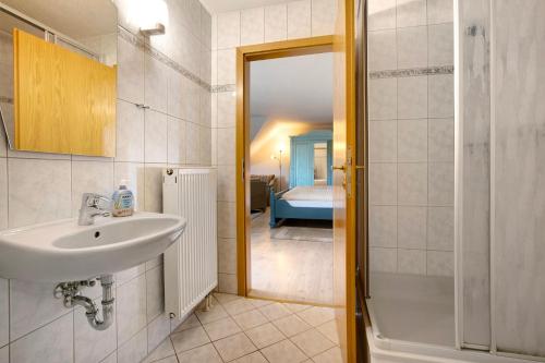 a bathroom with a sink and a shower and a bedroom at Pension Bergblick in Marienberg